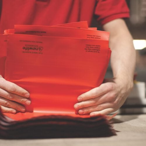 Operative folding a pile of mailing bags