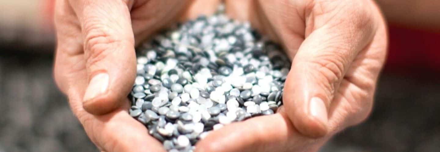 Up close image of someone holding pellets used to produce recycled mailing bags.