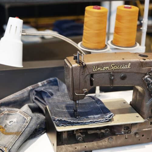 Nudie Jeans a pair on a sewing machine being fixed