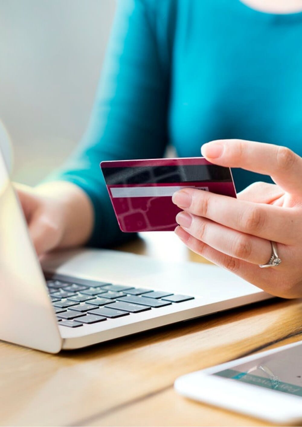Person on a laptop holding a payment card