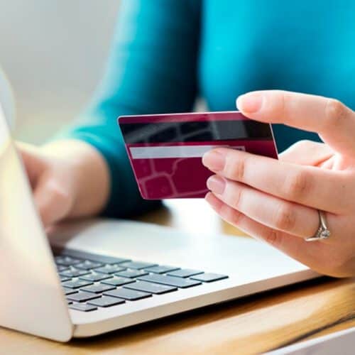 Person on a laptop holding a payment card