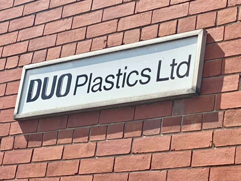 Original Duo Plastics Logo on building against a brick wall