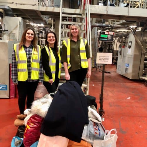 Georgia, Evi and Vicky with clothes donations on the scales